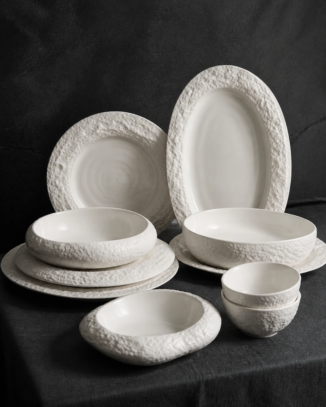 Crater white mineral textured dinnerware arranged on charcoal linen