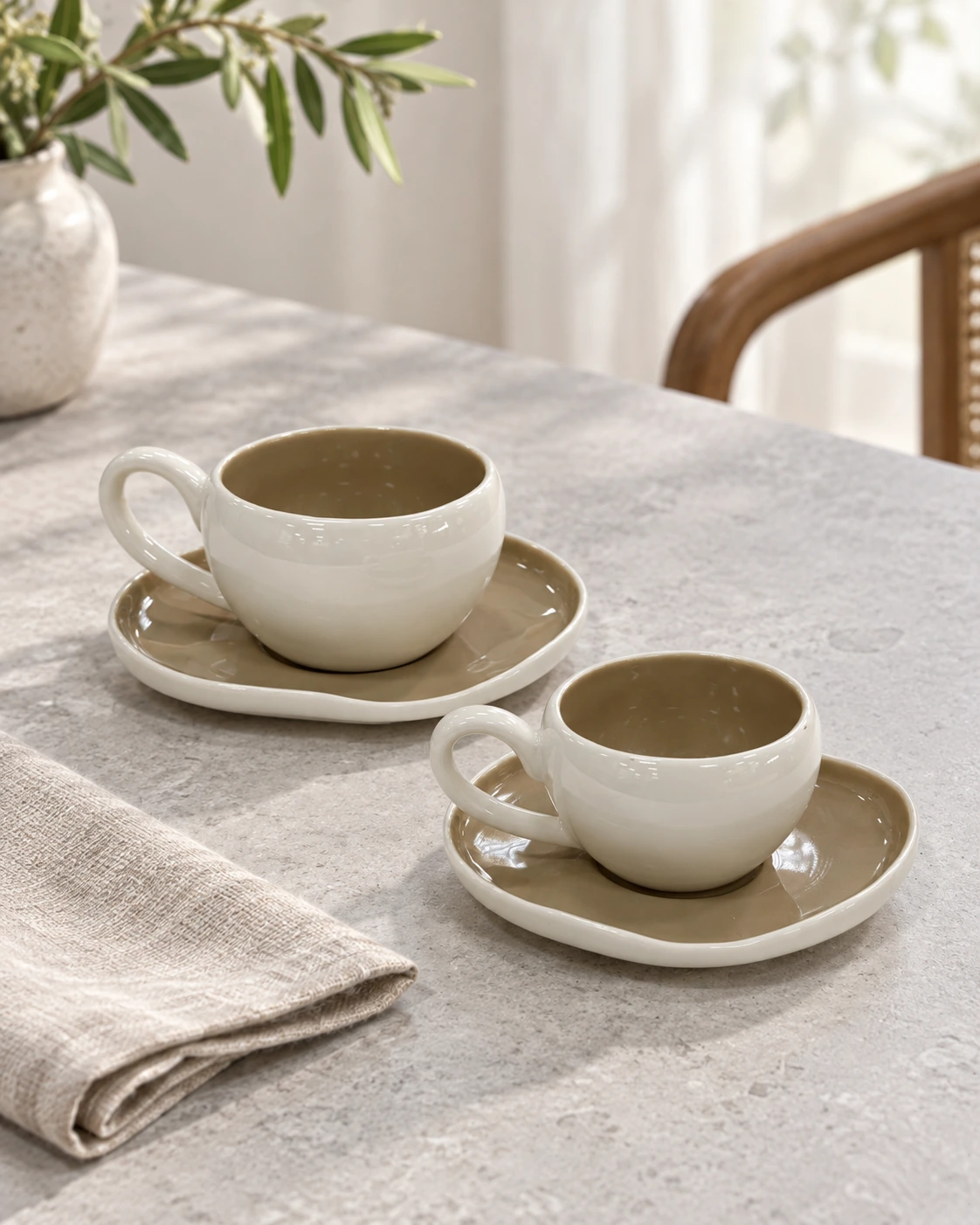 Porcelain cups and saucers with ivory exteriors and taupe interiors in a bright interior